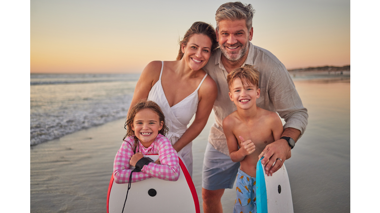 Surfing, happy family on a beach for holiday outdoor wellness, healthy lifestyle and development with love, support and care. Parents or mother and father with kids portrait with surfboard by ocean
