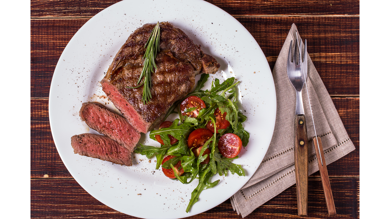 Ribeye steak with arugula and tomatoes.