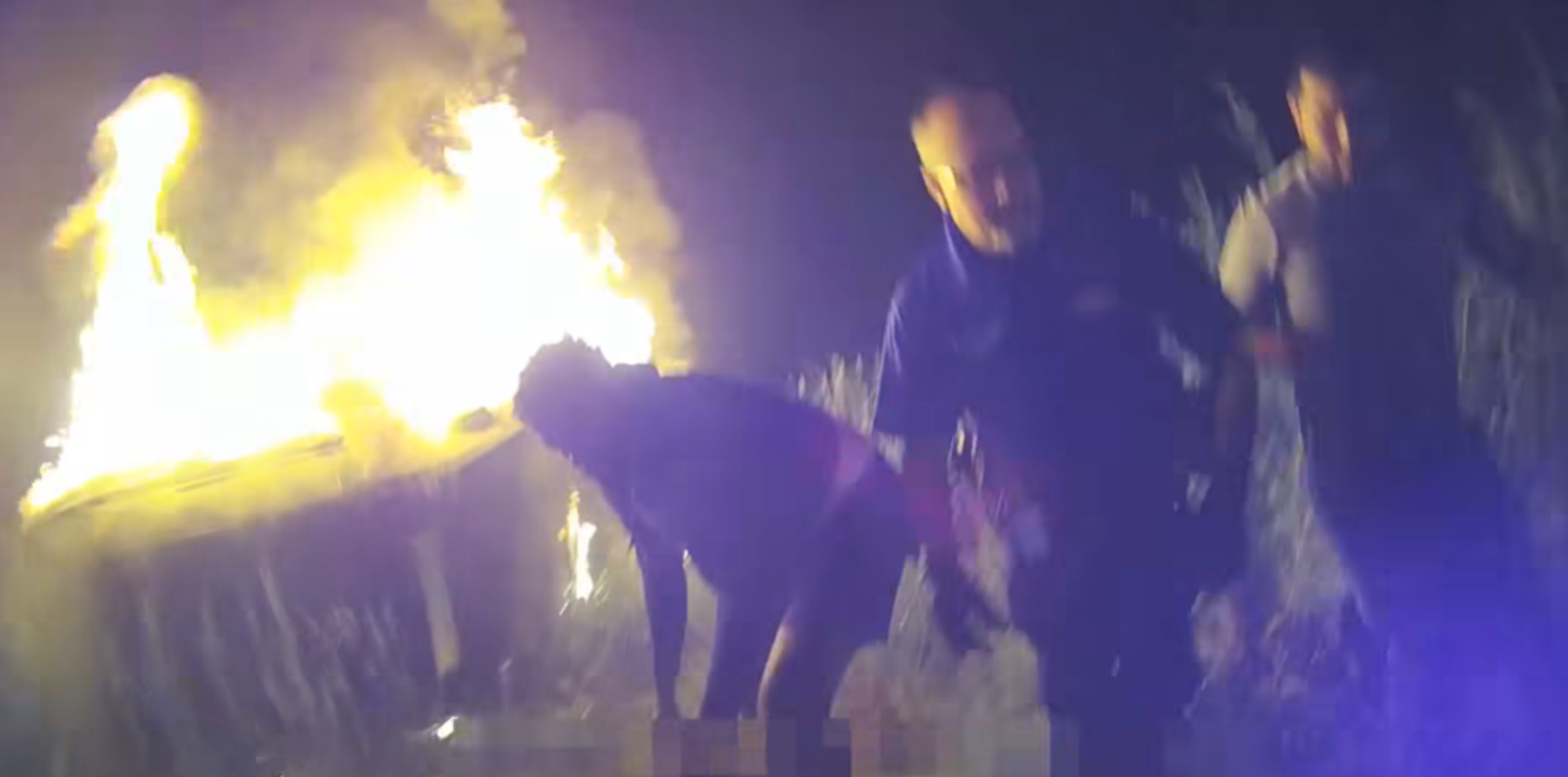 Police rescue a woman from a burning car