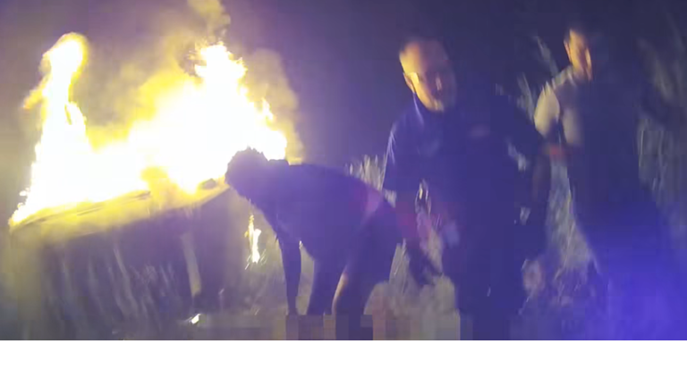 Police rescue a woman from a burning car
