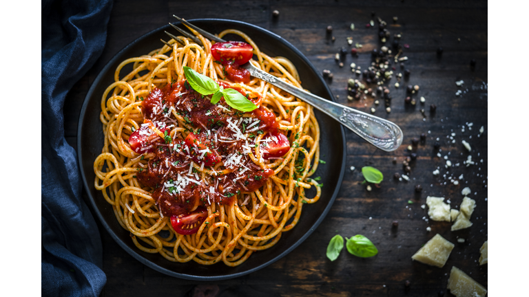 Spaghetti with tomato sauce shot on rustic wooden table