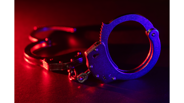 Silhouette of handcuffs. Image with the flashing red and blue police lights dark background.