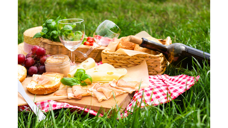 Picnic blanket with wine and food on green grass