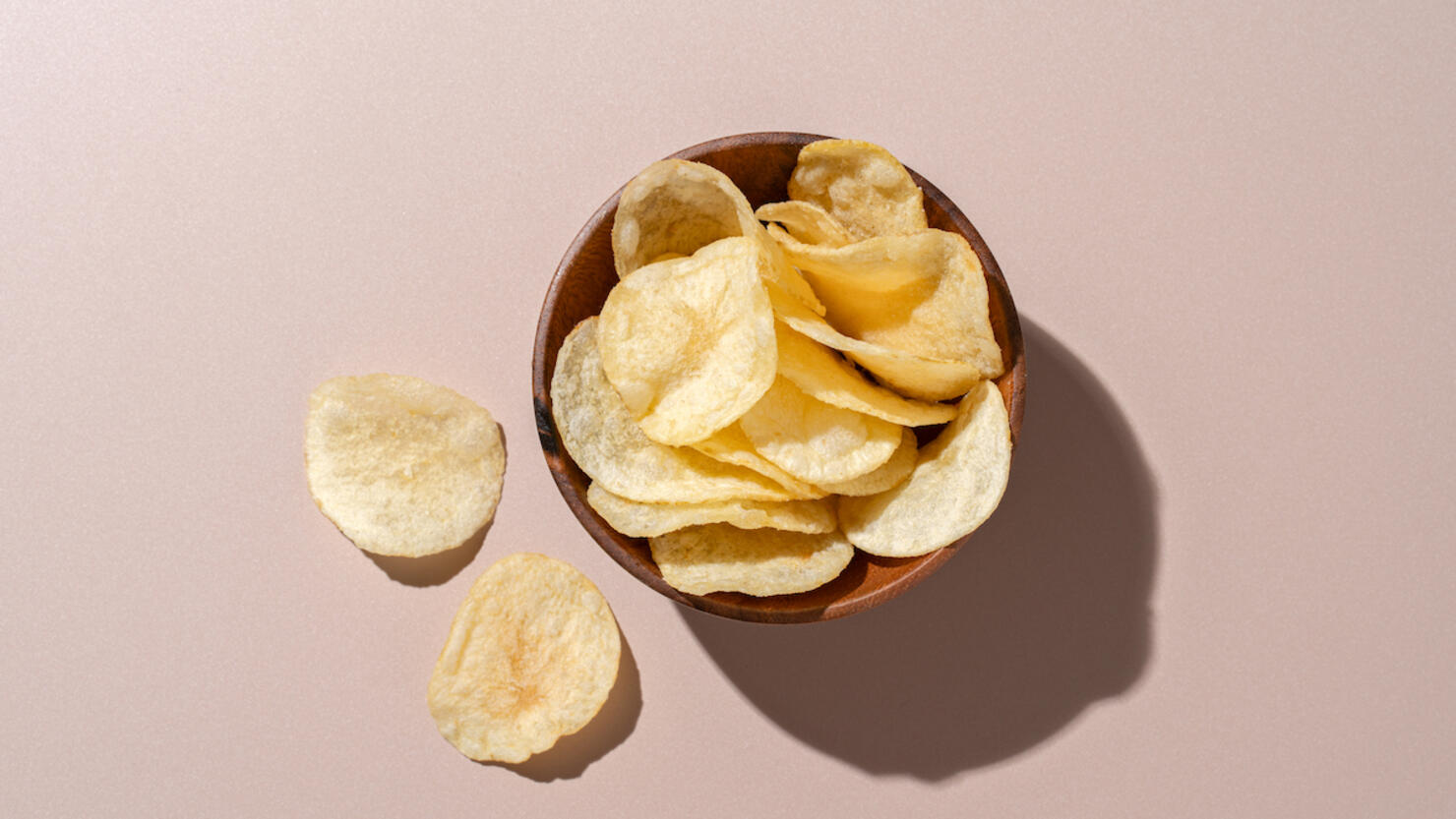 Bowl of Potato Chips on Brown Background