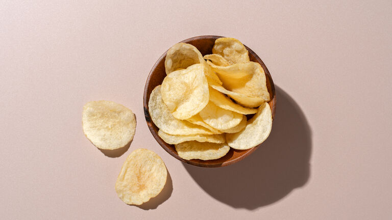 Bowl of Potato Chips on Brown Background