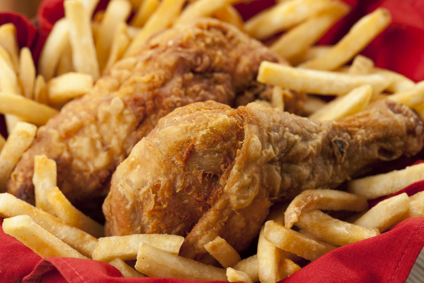 Golden fried chicken on a bed of French fries and red napkin