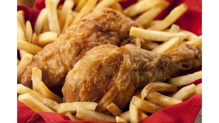 Golden fried chicken on a bed of French fries and red napkin