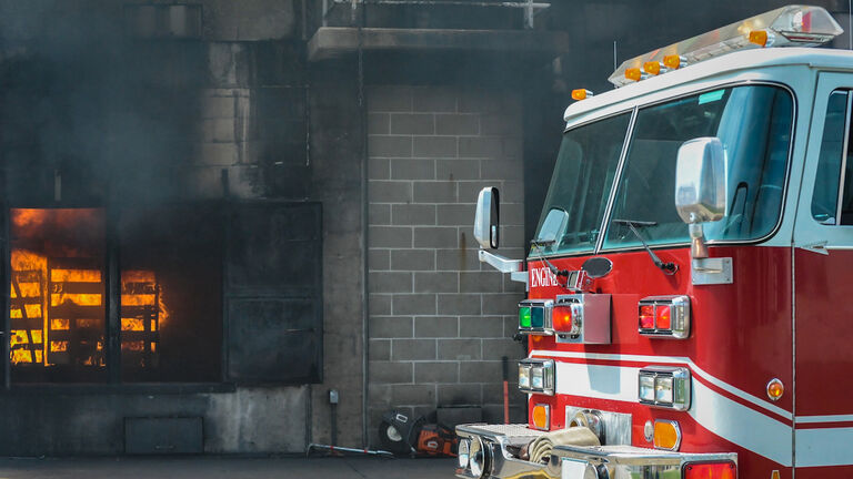 Fire and smoke at a burn building with a fire truck in front