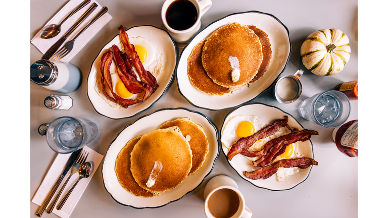 Pancakes with fried eggs and bacon served for breakfast in a diner, high angle view