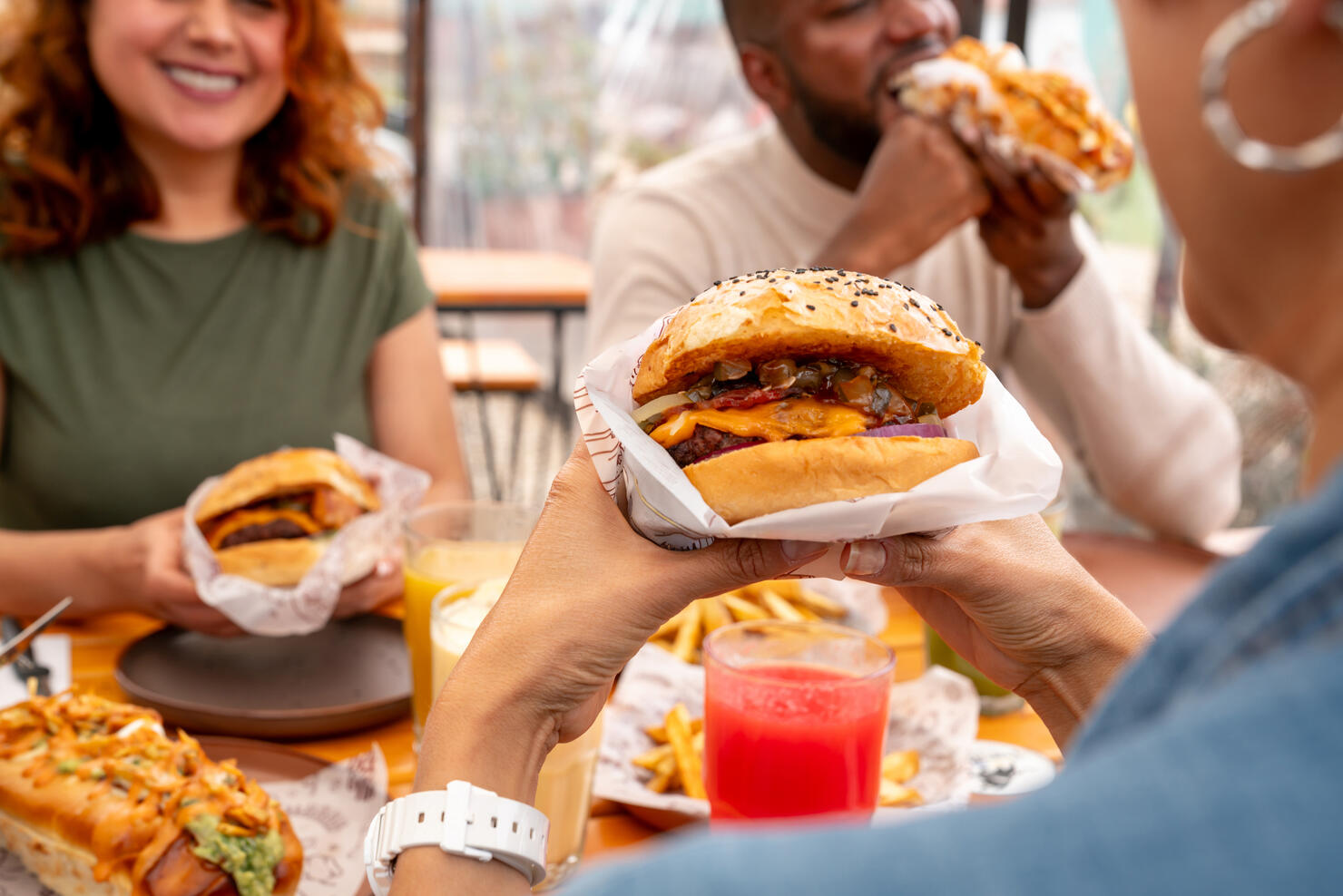 Close-up on a burger while people eat at a fast food restaurant