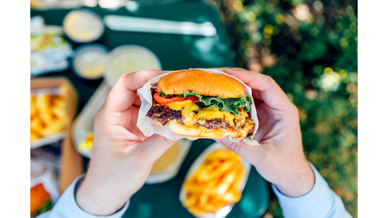 Man eating juicy cheeseburger, personal perspective view