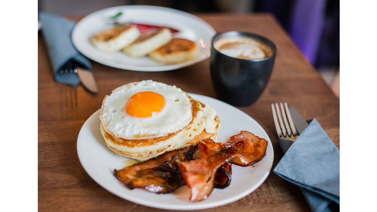 Tasty breakfast with pancakes, fried egg, coffee and bacon