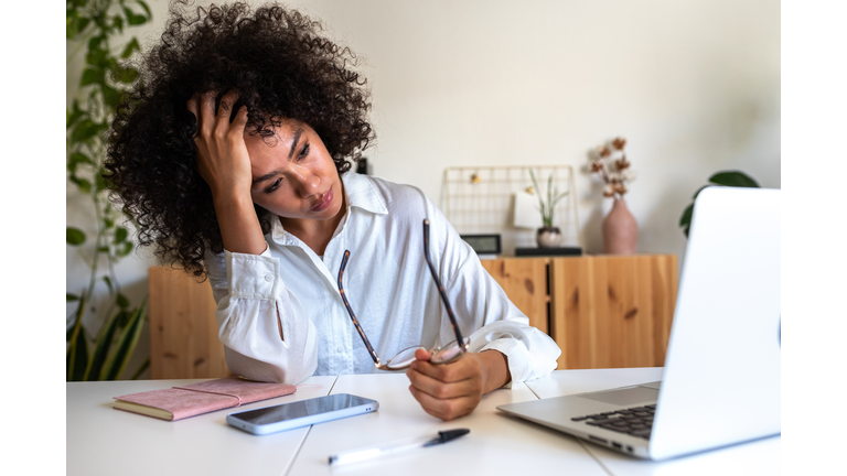 Young African American woman feeling exhausted and depressed sitting in front of laptop. Work burnout syndrome.