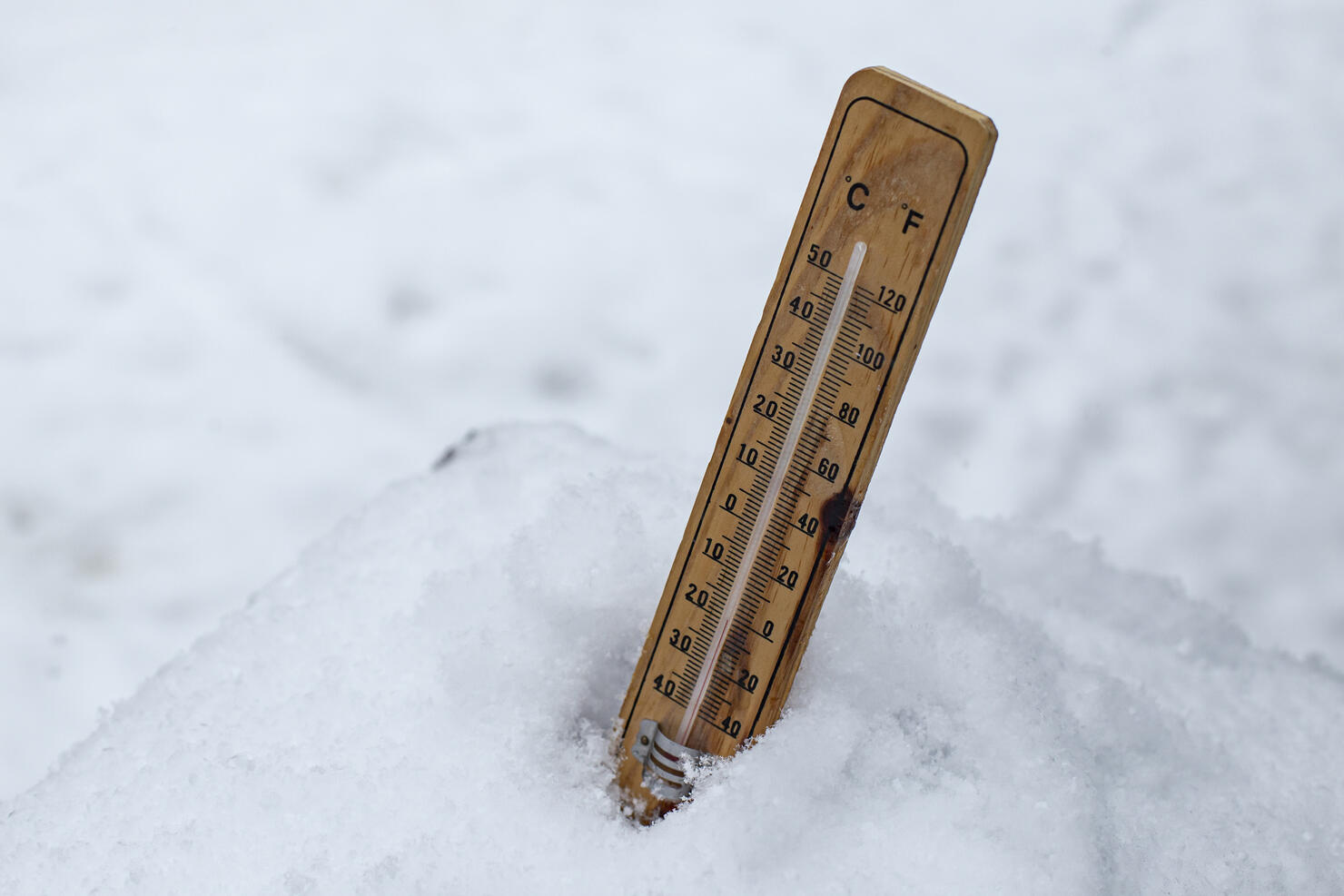 Thermometer plunged in a pile of snow, white weather background