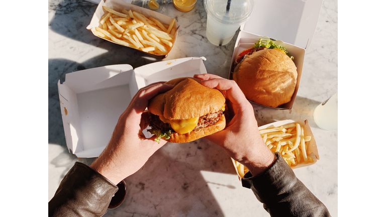 Man eating a cheeseburger with french fries, personal perspective view