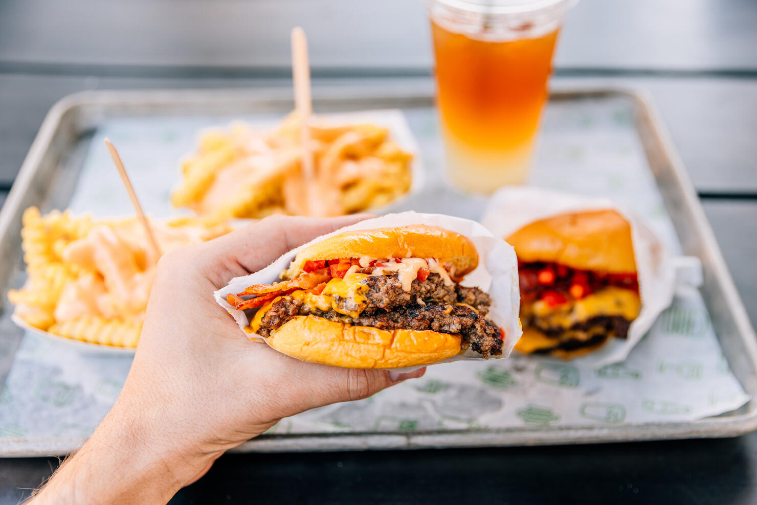 Person eating double cheeseburger with bacon at a fast food joint, personal perspective view