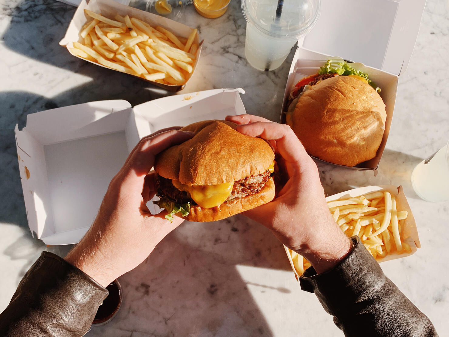 Man eating a cheeseburger with french fries, personal perspective view