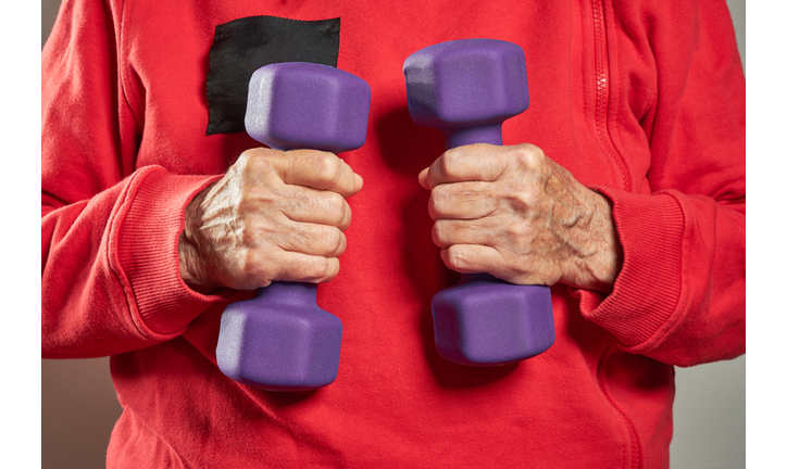 Lilac small dumbbells in the hands of an elderly woman.