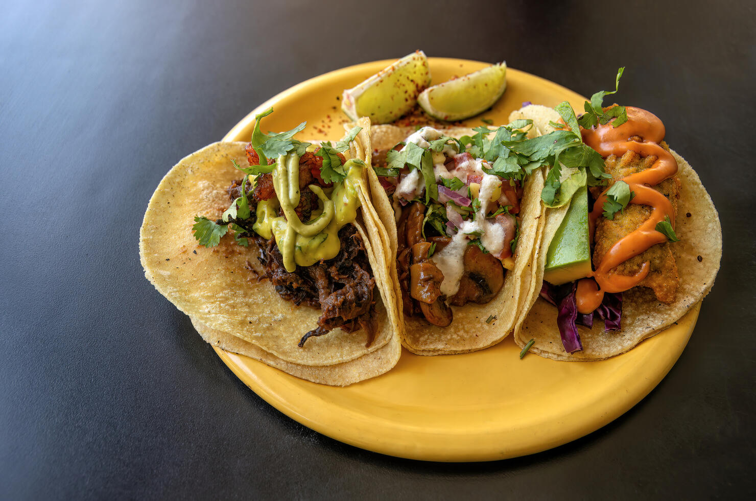 Trio of vegan tacos, from left: fried hibiscus flower, guacamole, ripe plantain cubes and cilantro mayonnaise; tequila mushrooms, mango pico de gallo and sour cream; and fried tempura tofu avocado slices, purple cabbage and chipotle mayonnaise