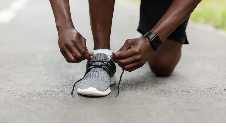 Closeup of african guy fixing his sport shoes