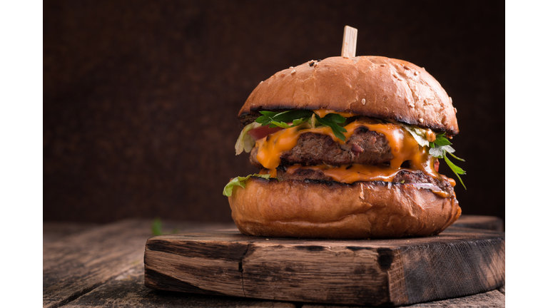 Tasty grilled burger with lettuce and mayonnaise , rustic wooden table