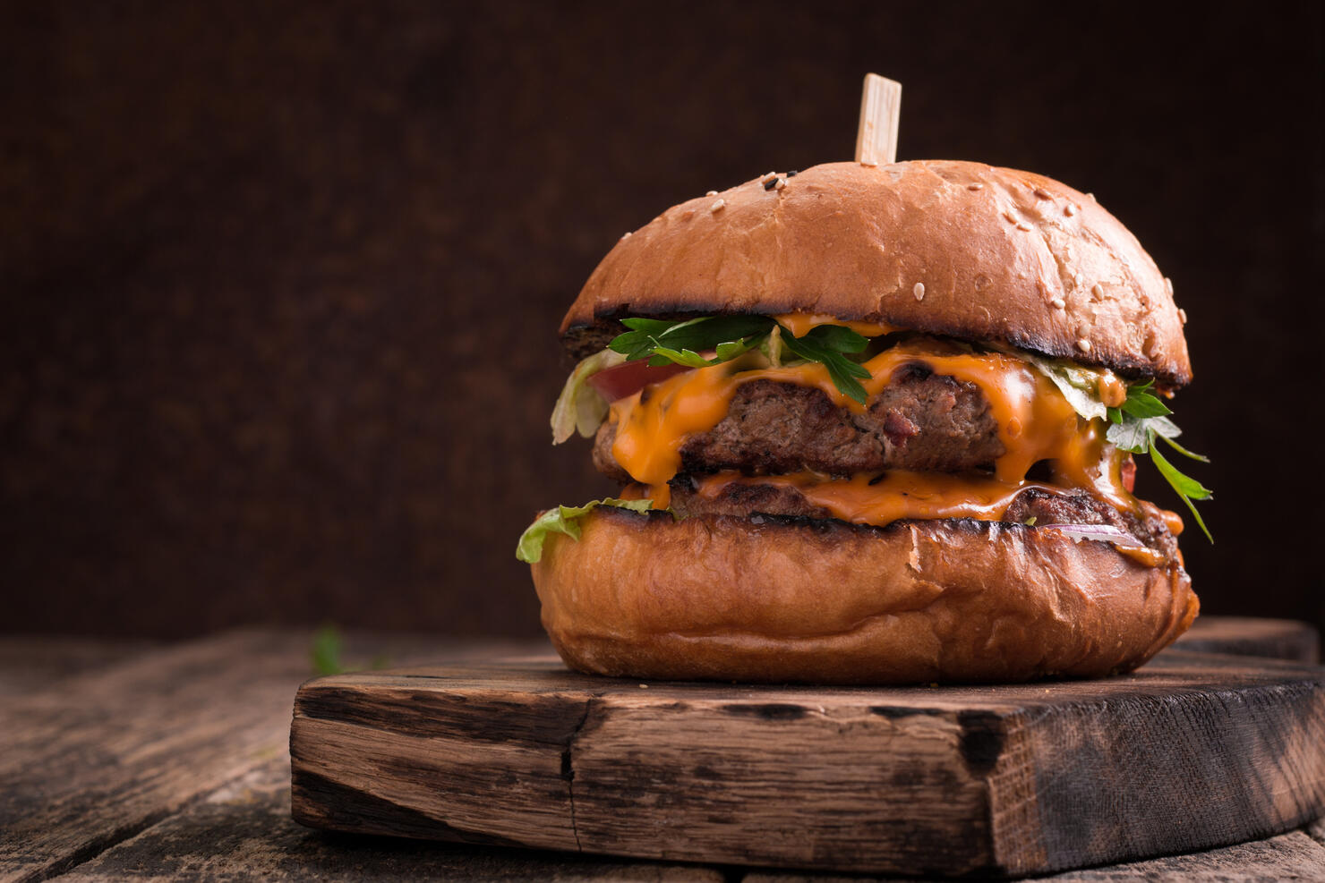 Tasty grilled burger with lettuce and mayonnaise , rustic wooden table