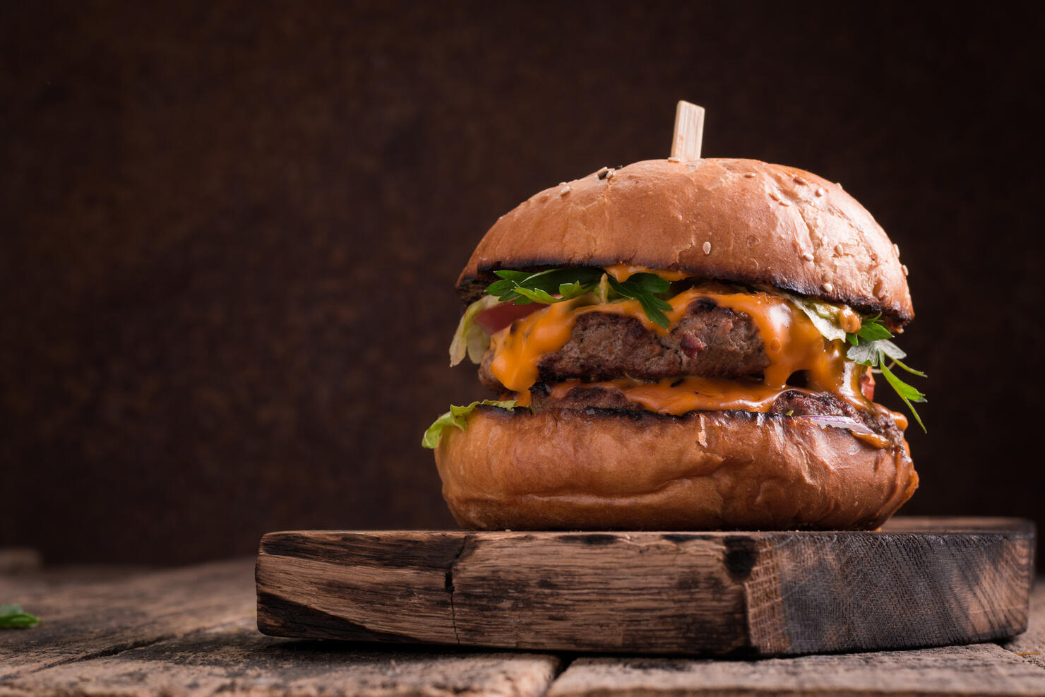 Tasty grilled burger with lettuce and mayonnaise , rustic wooden table