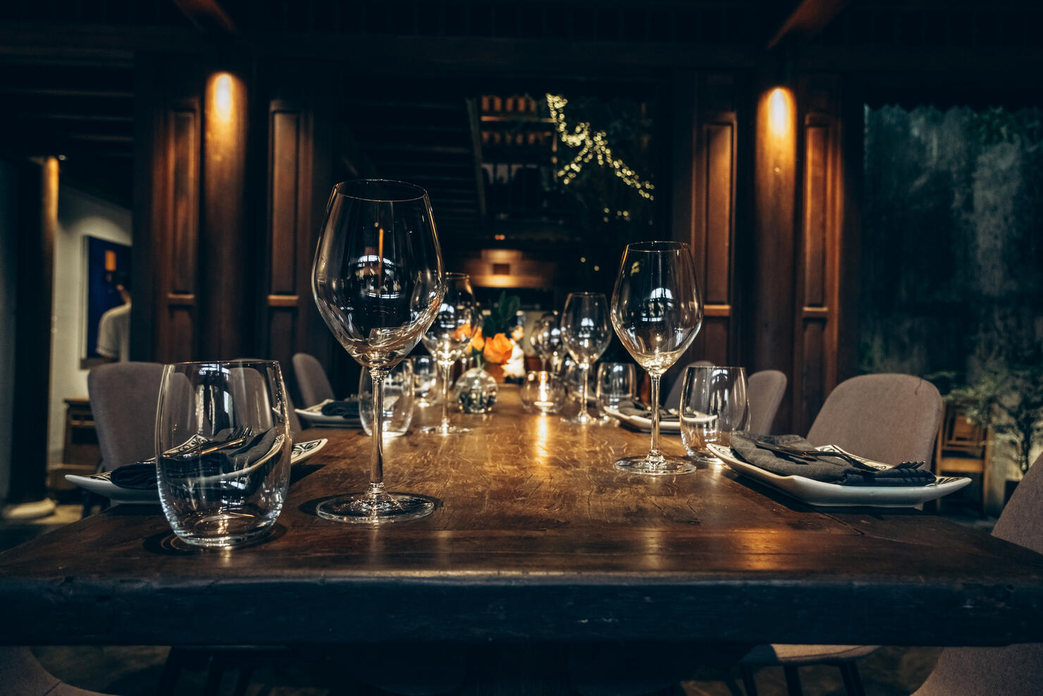 Elegant table setting in fine dining room. Beautifully set dining table with wine glasses in a dimly lit, upscale house.