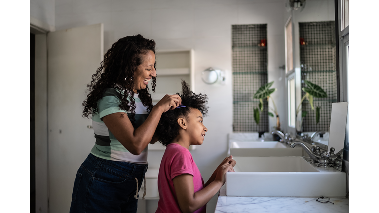 Mother combing daughter's hair at home
