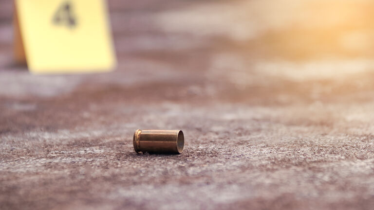 Spent bullet casing lying on the ground with blur number 4 sign. Concepts of shooting sports and security highlighting the dual nature of firearms in both competitive sport and protective measures.