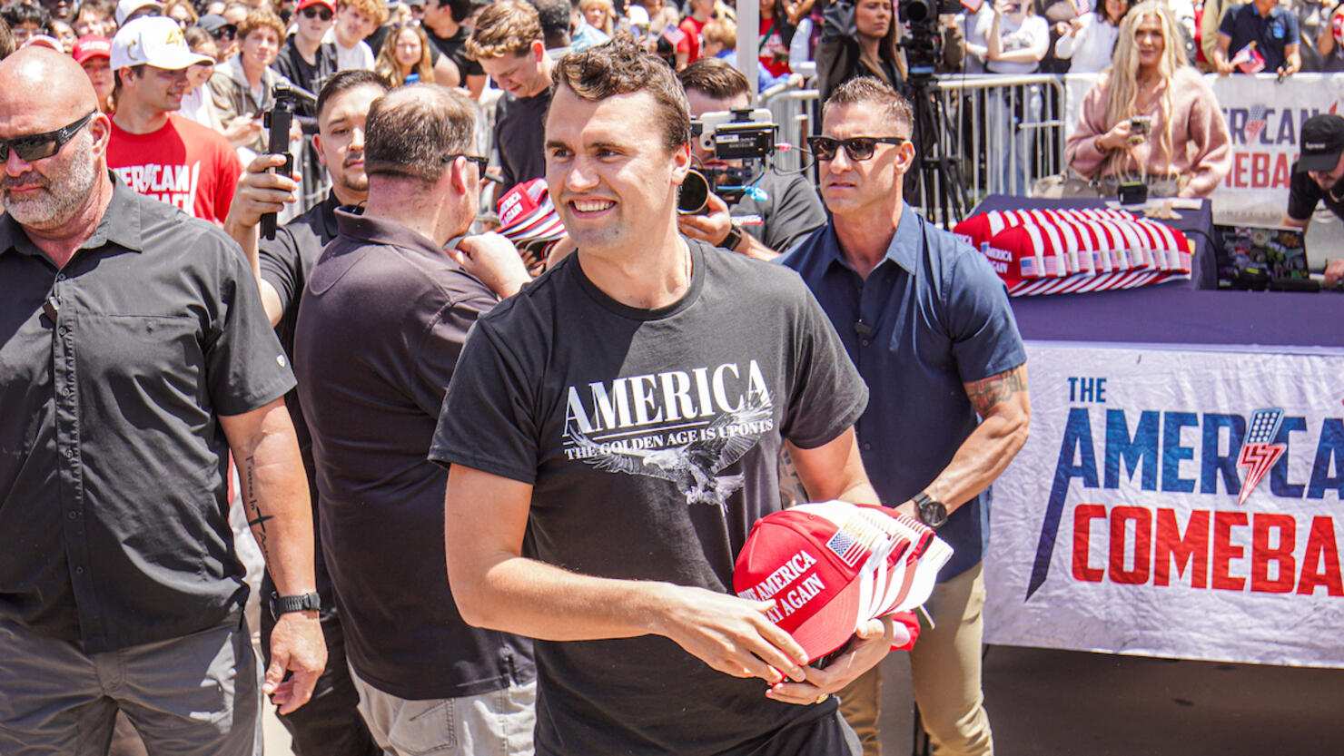 Charlie Kirk, founder of Turning Point USA, throws hats to