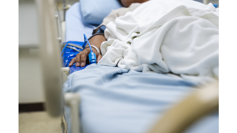 Patient Lying in Hospital Bed Monitored with Medical Device Attached to Finger