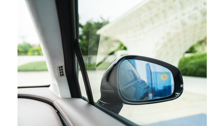 Car window side mirror on sunny day with truck traffic in reflection in Richmond