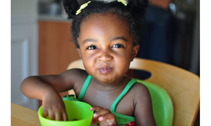 A young girl eating grapes out of a bowl