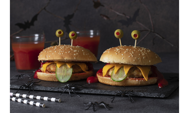 Two funny monster chicken burger with toast cheese, ketchup, olives and cucumber. Creative Halloween food