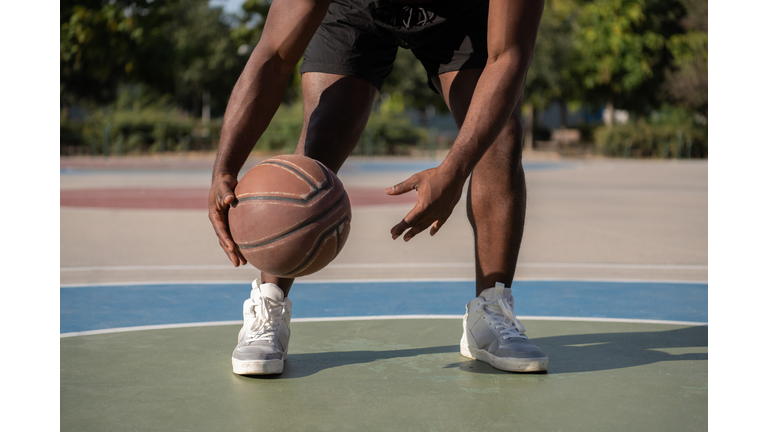 Cropped black athlete dribbling basketball ball