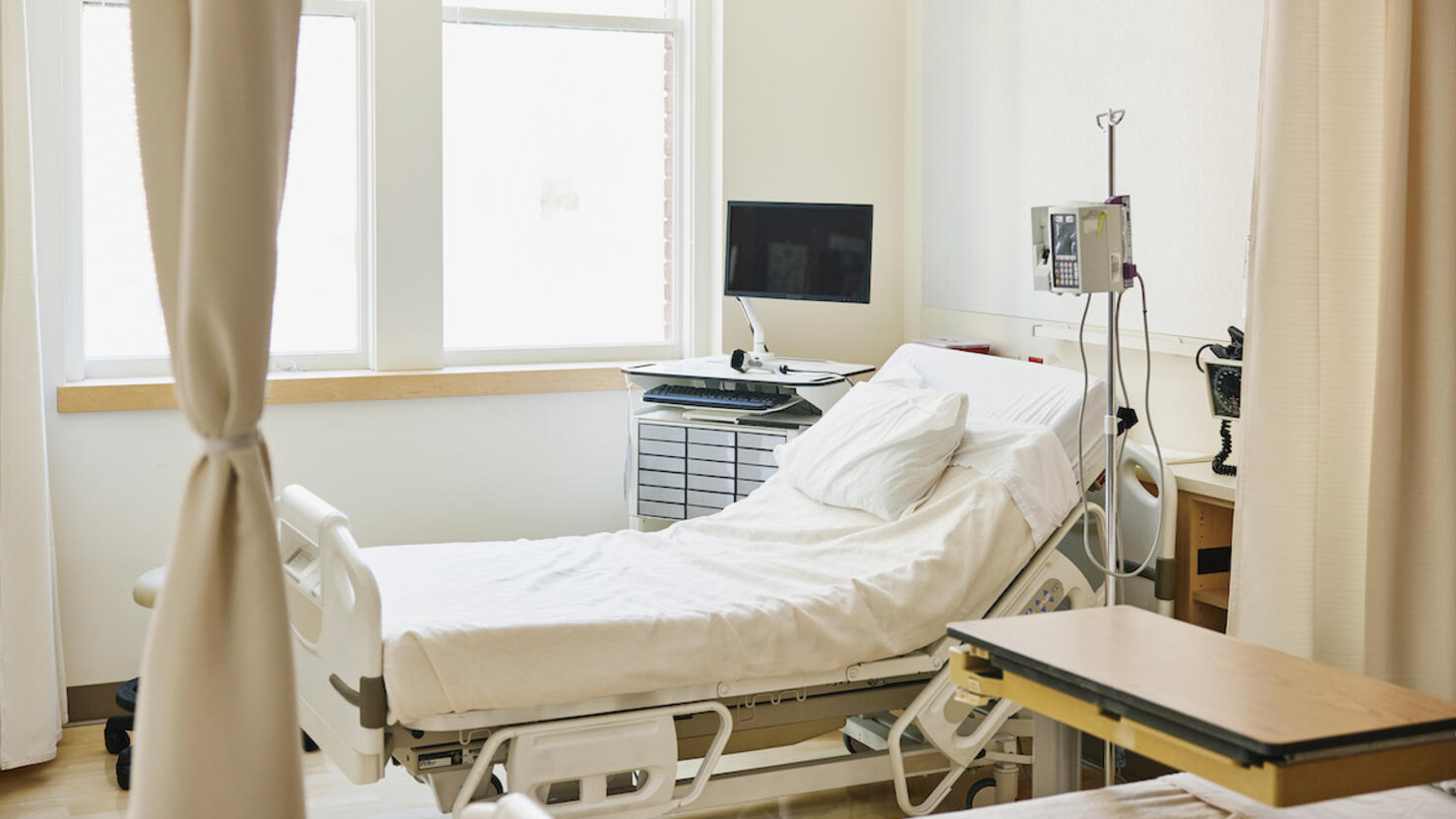 Wide shot of empty hospital bed in emergency room
