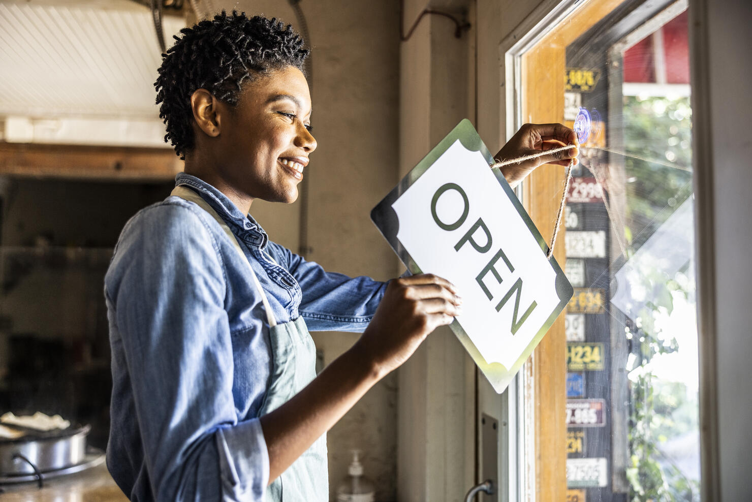 Female small business owner placing open sign in business window
