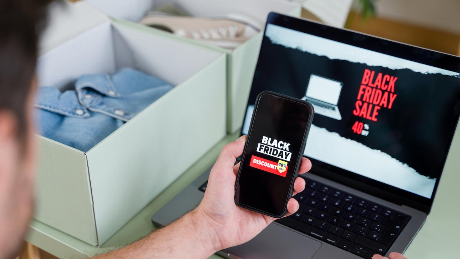 Man shopping online during black friday using laptop and smartphone