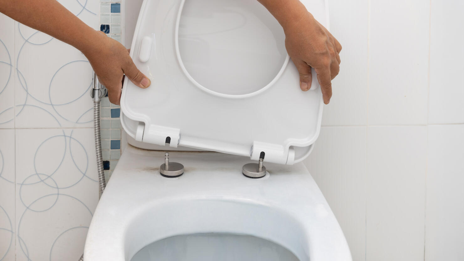 Handyman replace toilet seat cover.  Bathroom toilet seat replacement concept.