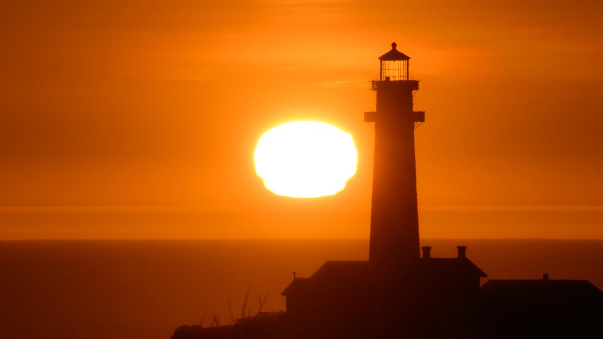 Sun sets behind the Pigeon Point Lighthouse in California